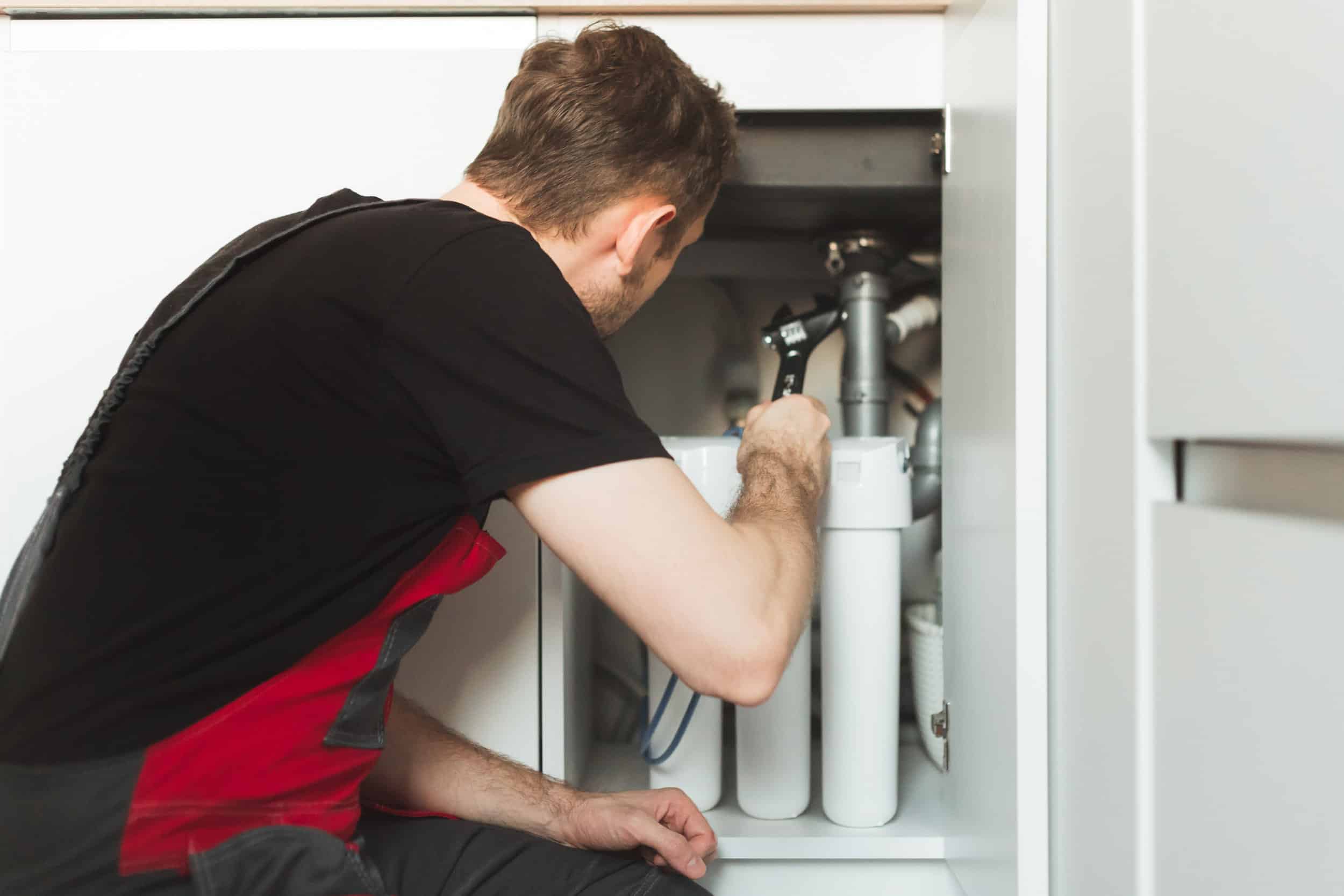 Homme reparant un adoucisseur eau